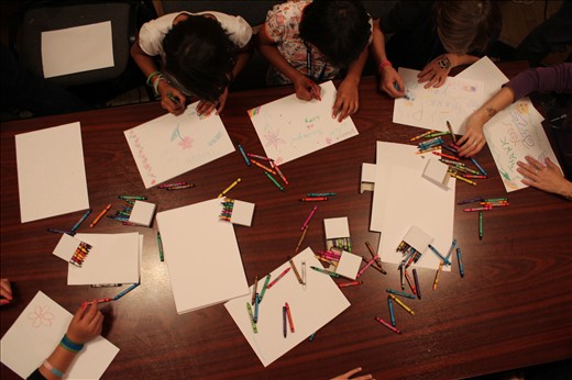 Rainbows: crayons and paper are strewn over the table at a girls' home after dinner, a time to explore creativity and complete homework.