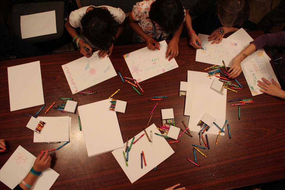 Rainbows: crayons and paper are strewn over the table at a girls' home after dinner, a time to explore creativity and complete homework.
