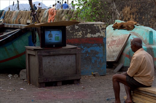 The fisherman watching a classic Amitabh Bachaan movie, right on the dockyard.