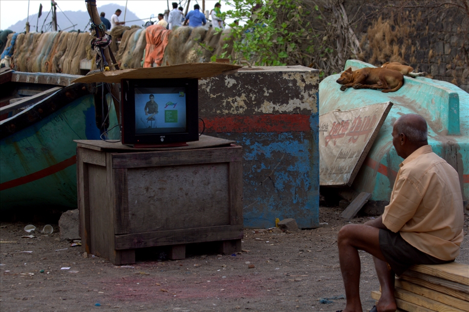The fisherman watching a classic Amitabh Bachaan movie, right on the dockyard.
