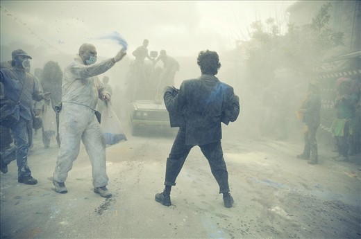 Thousands of people march through the town throwing flour at one another