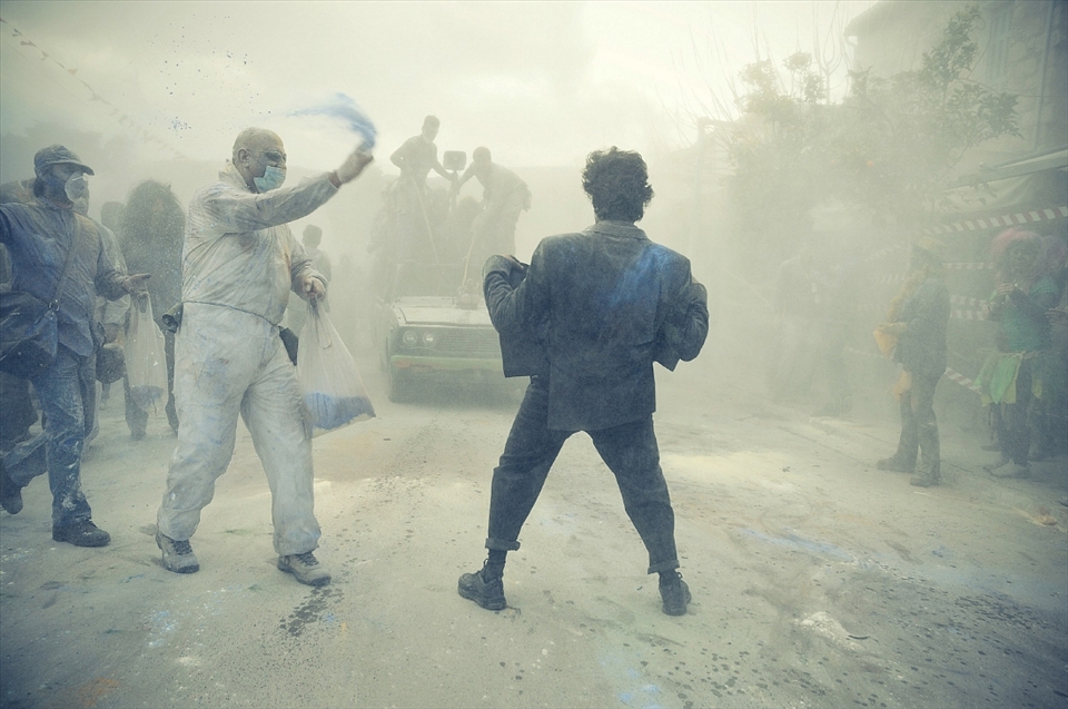 Thousands of people march through the town throwing flour at one another