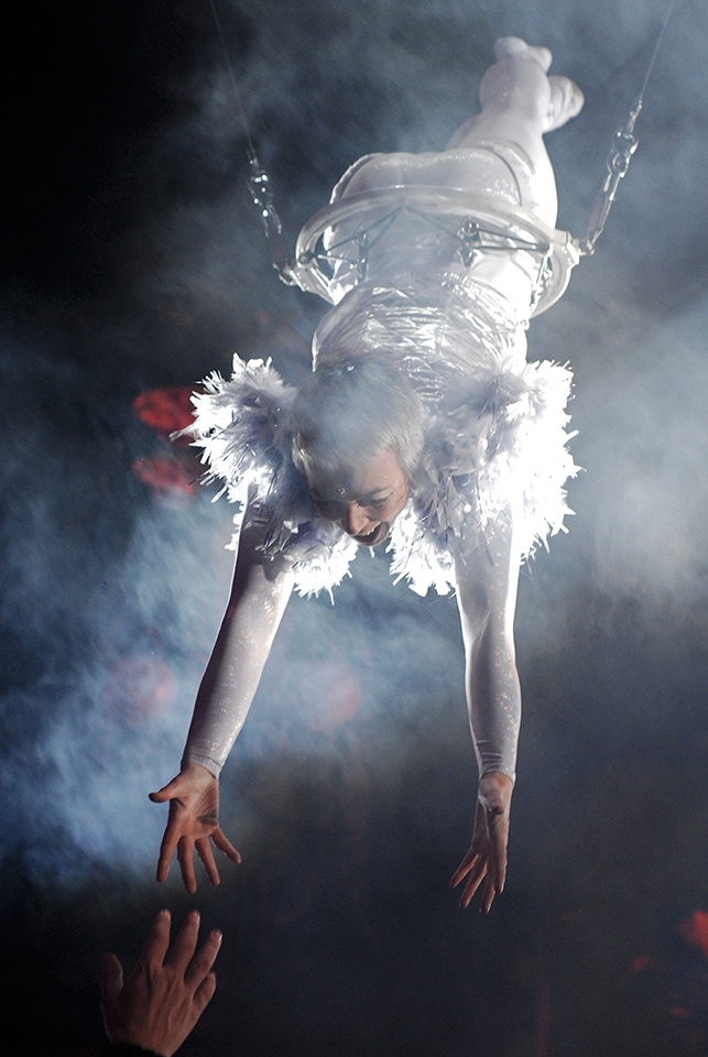 Opening Ceremony. A hand from the audience tries to touch the flying acrobat.