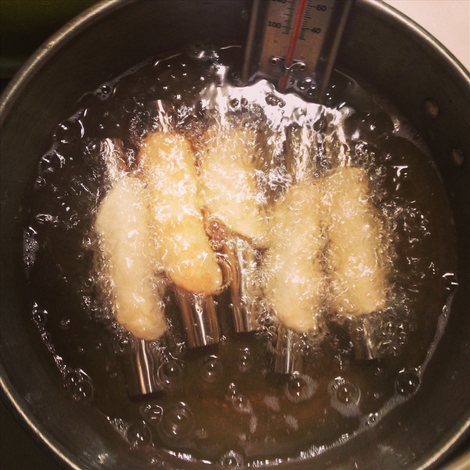 Cannolis frying to a crispy golden brown.