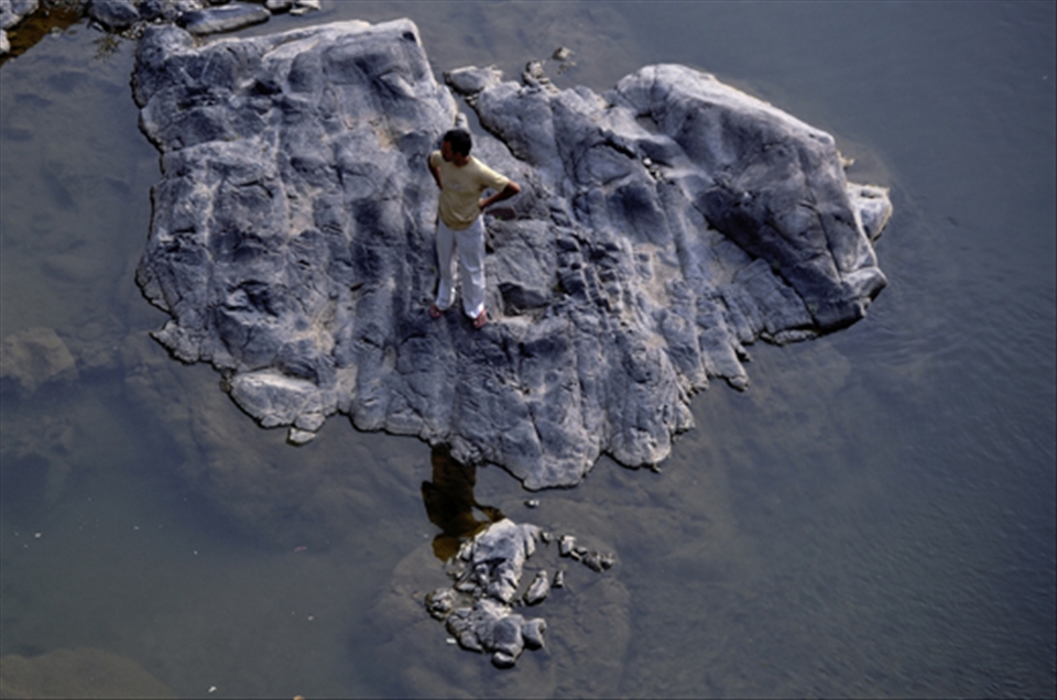 In a middle of river man was satnding in a big stone with his own