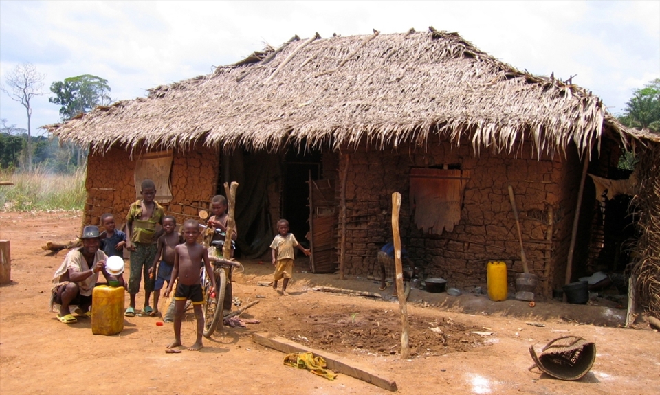 A man cycles home with a jerry can of water from the nearest river. Children wait to have a sip.