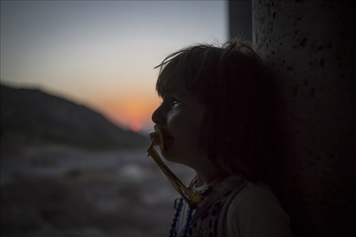 A Yazidi young girl cries inside an unfinished building.