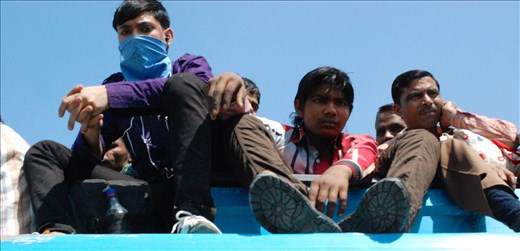 Men of all ages sit atop a full bus on their way to work in the morning.