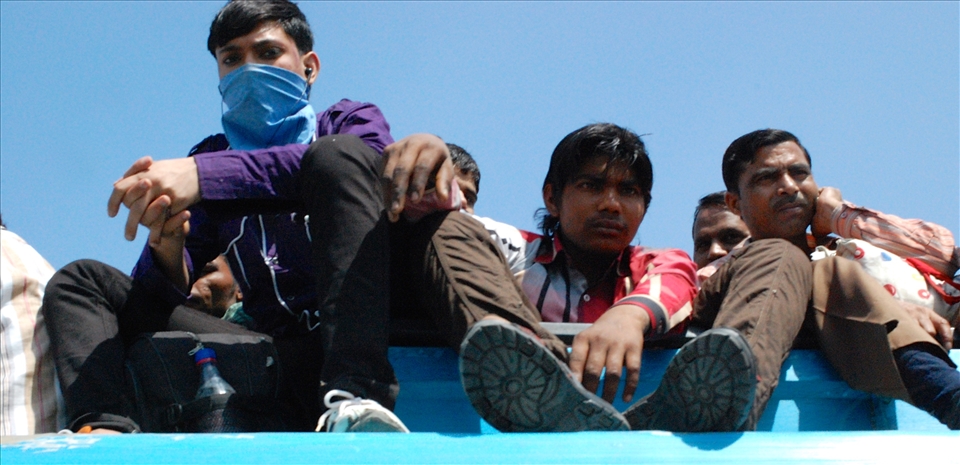 Men of all ages sit atop a full bus on their way to work in the morning.