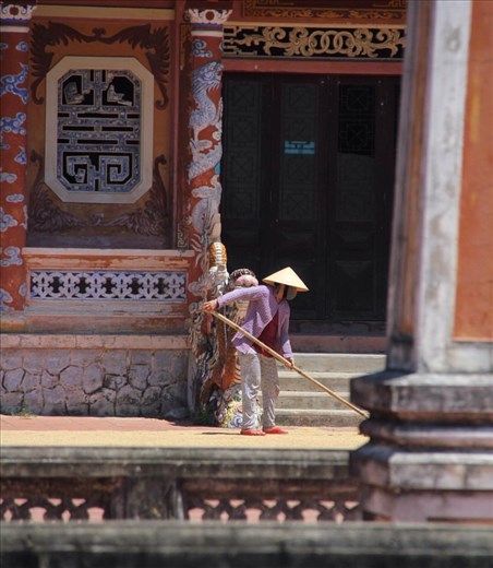 Lady drying her rice in front of the local temple. 