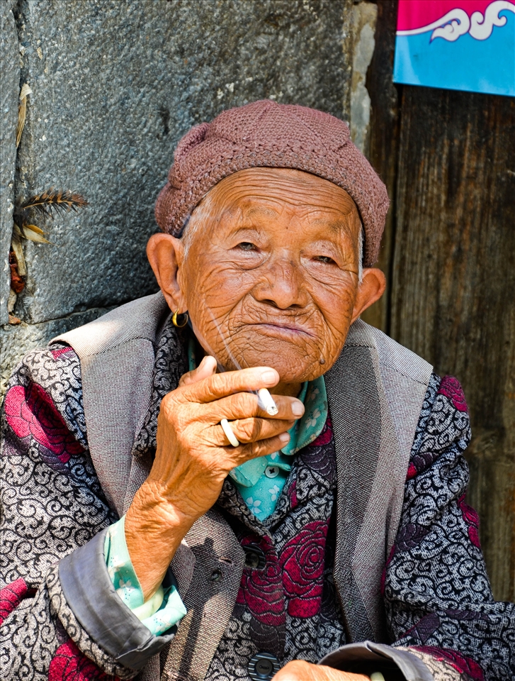 An old lady sitting by the road asking for cigarettes. 