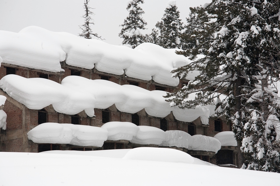 An abandoned hotel project sits laden with snow on a hill side. A silent reminder of the precarious tourism industry along 