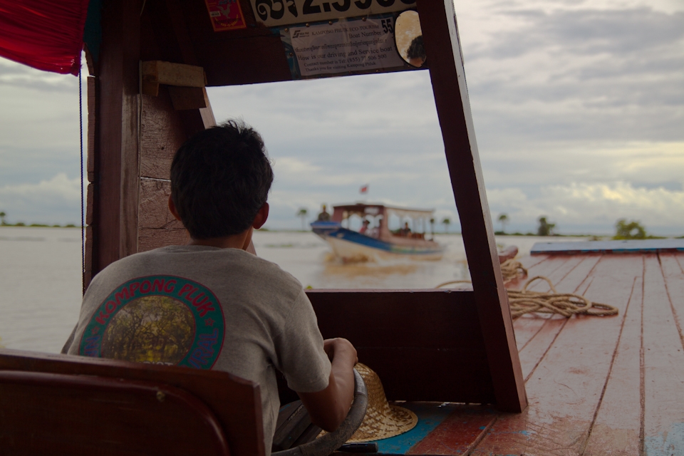 A Cambodian boat driver navigates the waters near Angkor, towards Kompong Pluk.