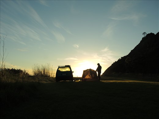 Andrew packs up the tent on the last morning of a road trip in Northland, NZ.