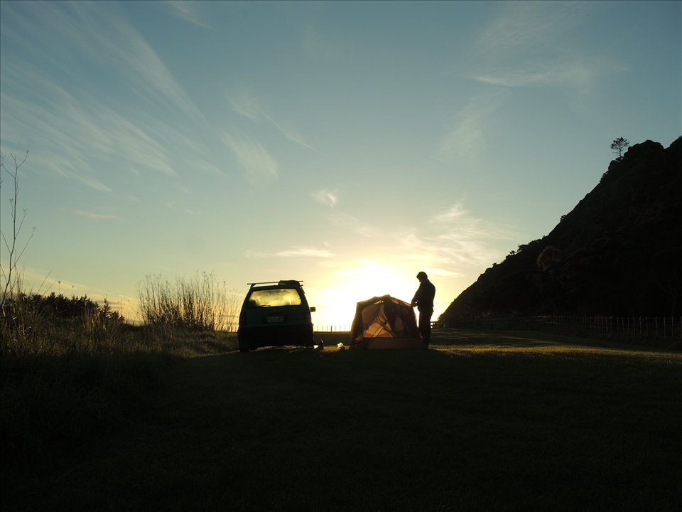 Andrew packs up the tent on the last morning of a road trip in Northland, NZ.
