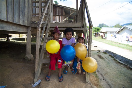 Children taking the merry making outside, watching the others kick a soccer ball