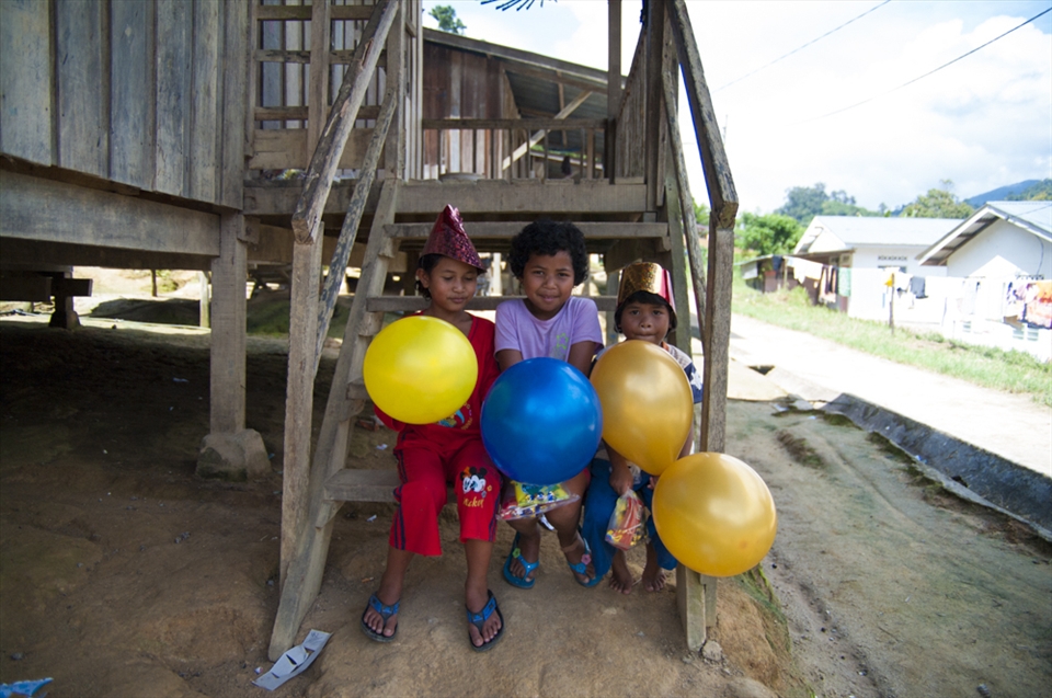 Children taking the merry making outside, watching the others kick a soccer ball