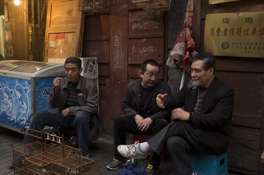A group of old men take a smoke break behind the kitchen where they work. Every aspect of life happens in the streets of Xi'an.  