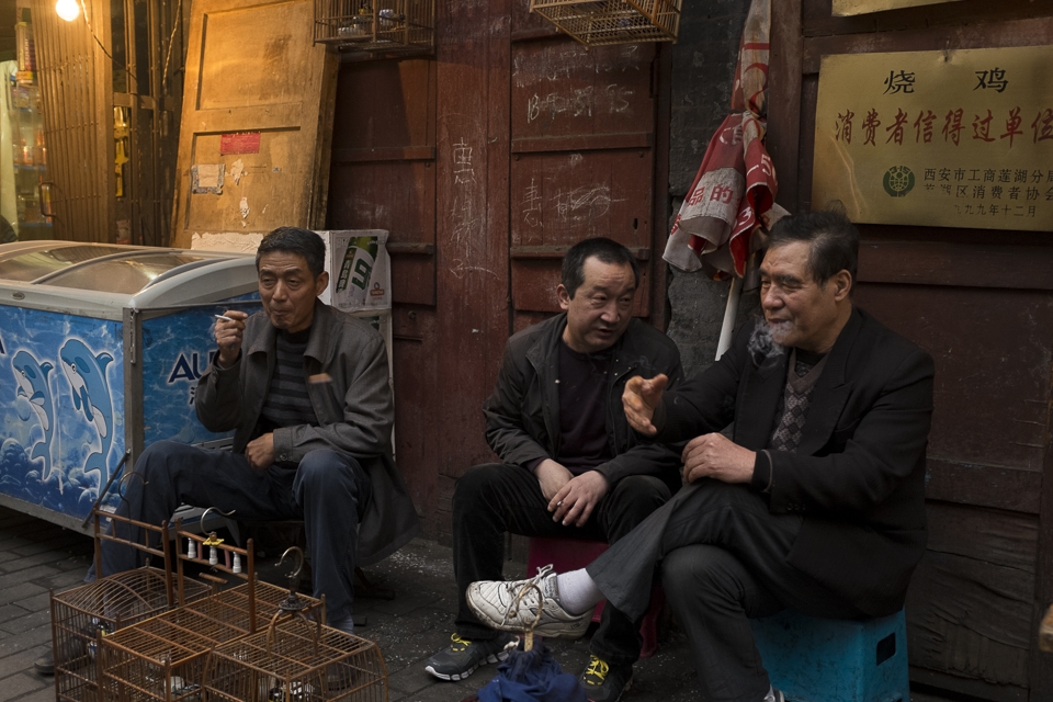 A group of old men take a smoke break behind the kitchen where they work. Every aspect of life happens in the streets of Xi'an.  