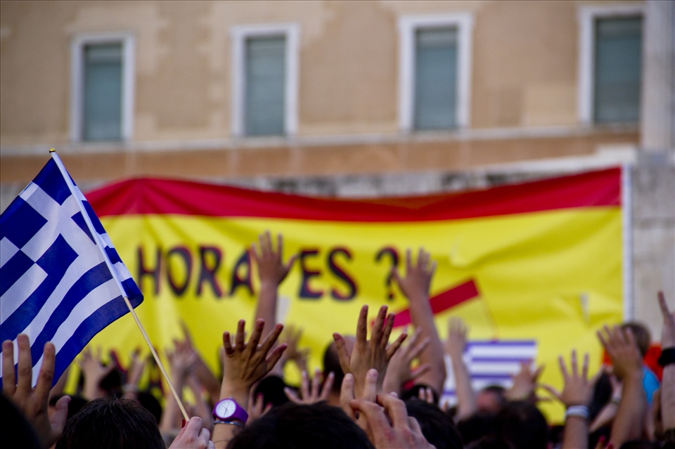 Greeks gesturing against the Greek Parliament alongside with Spanish protesters.