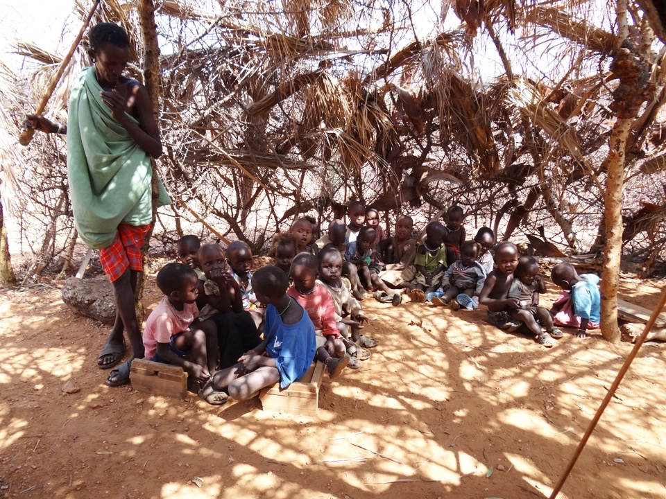 SCHOOL TIME - The children sit in their 'classroom' made from trees, sticks and leaves. Led by their teachers, they sing to us in Swahili and then also show us how they are learning English too by reciting the alphabet for us.
