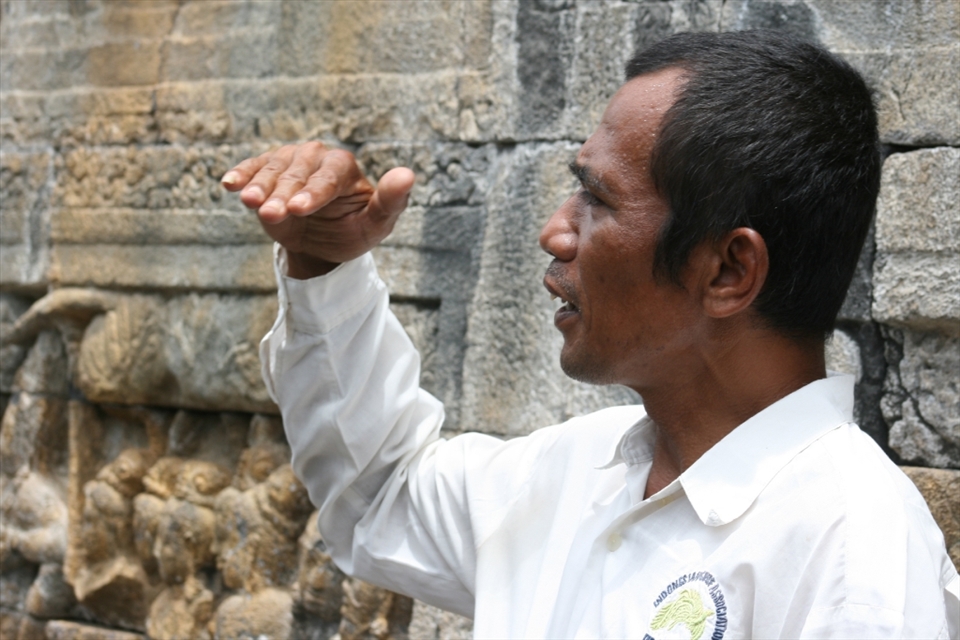 The guide will help you to understand the history of Borobudur temple. He tells of relief on the wall. (Borobudur, Magelang, Central Java)