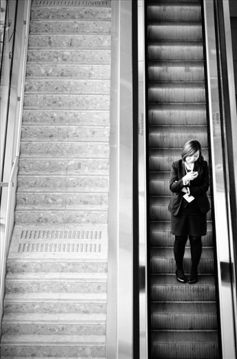 Watch Your Step. The woman is getting down using the escalators but she is focusing with her phone. So becareful.. watch your step girl..