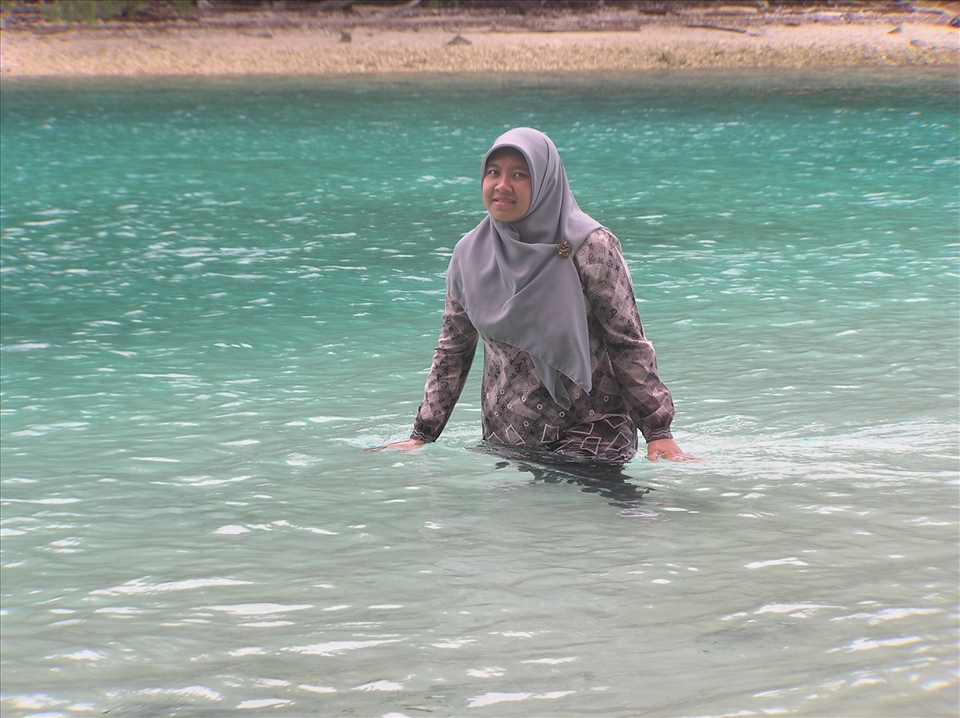 My friend, Indah, playing with the beautiful green-blue sea water in Air Island