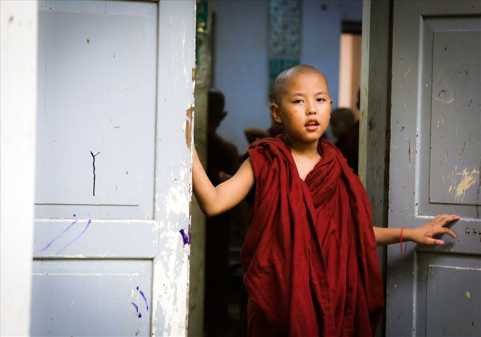 A young monk peers through the window of the monastary. (Myanmar)