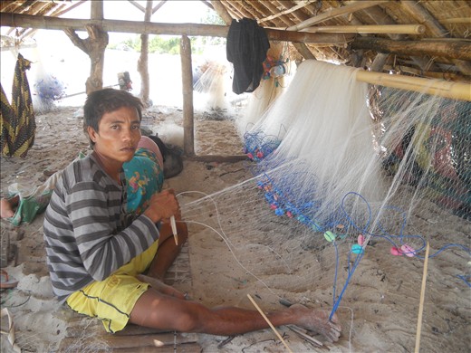 A fisherman were knitting his net under the smal tradisional fishing house