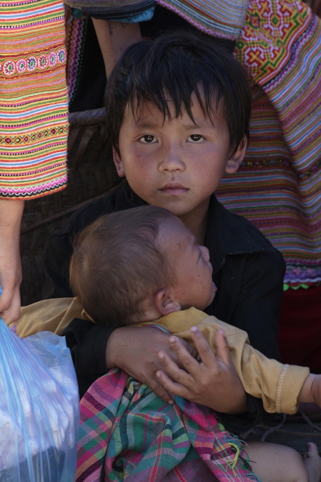 A Hmong Boy trying to calm down his little brother while his parents are busy with selling at the local market in Bac Ha. Responsibility comes early in the remote villages of Northern Vietnam, Family is everything.
