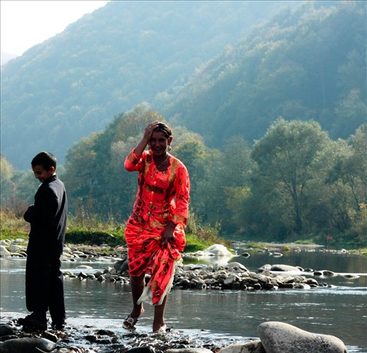 Gypsy girl crossing the creek in Negreni at the annual flea-market in October. Many gypsy families come to the market from afar, some of them still come by horses and carts. They sleep in tents in the nearby forests and wash in the creek by Negreni. This young girl looked like a wonder, so beautiful so I couldn't keep my eyes off her and when she crossed the creek, and most likely the cold water tickled her feet, I managed to captured her smile, which was shy and playful in the same time.