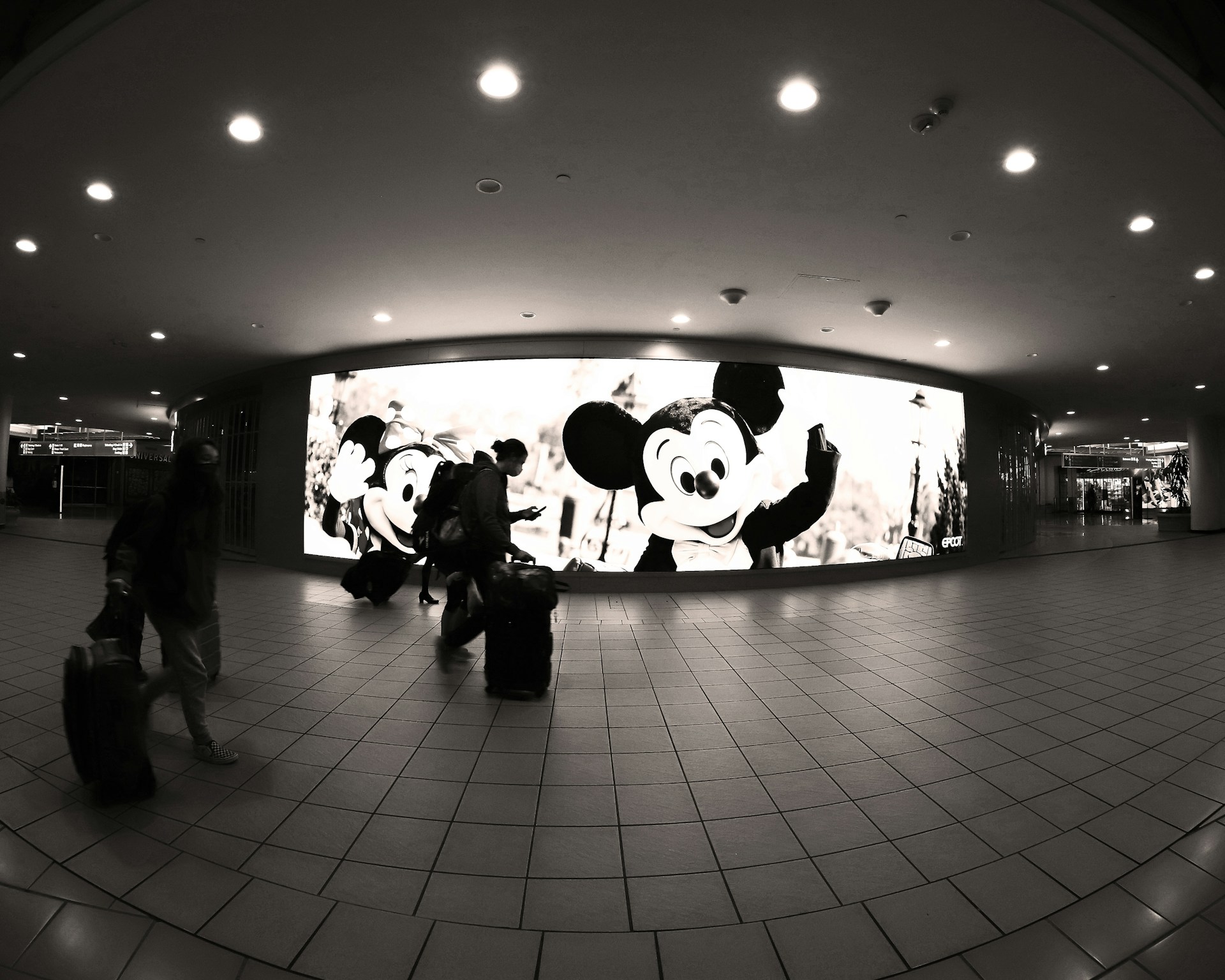 airport walkway with illuminated Mickey Mouse advertisement