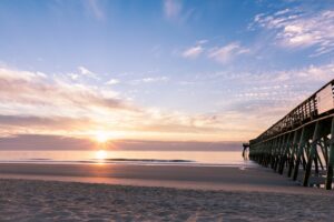 silhouette photography of black wooden pier near shoreline during sunrise