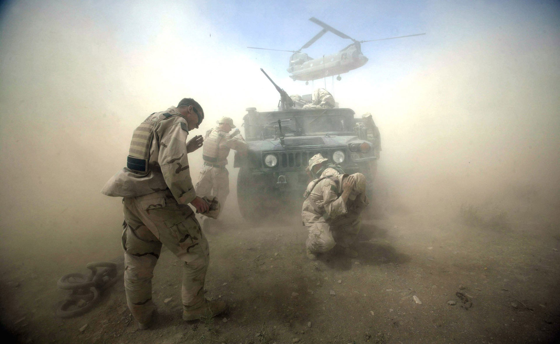 Soldados estadounidenses tratan de luchar contra el incómodo polvo que levantan los rotores del helicóptero Chinook en la provincia de Kadahar, en Afganistán