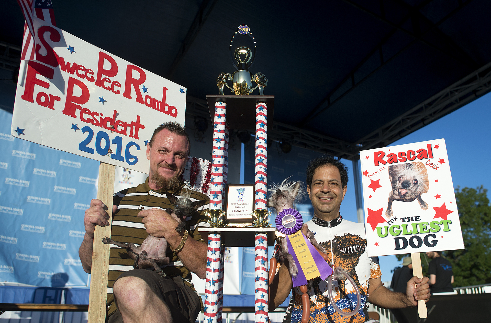 Sweepie Rambo con su propietario Jason Wurtz junto a Rascal Deux y su dueño Dane Andrew, durante la competición del perro más feo del mundo (AFP)