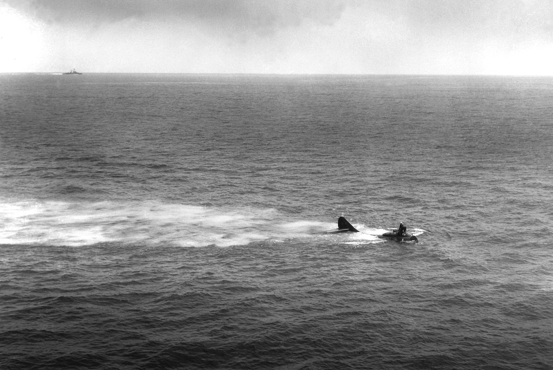 Un avión F9F-2 flotando en el mar después de un accidente, mientras un buque va a su rescate (US Department of Defense)