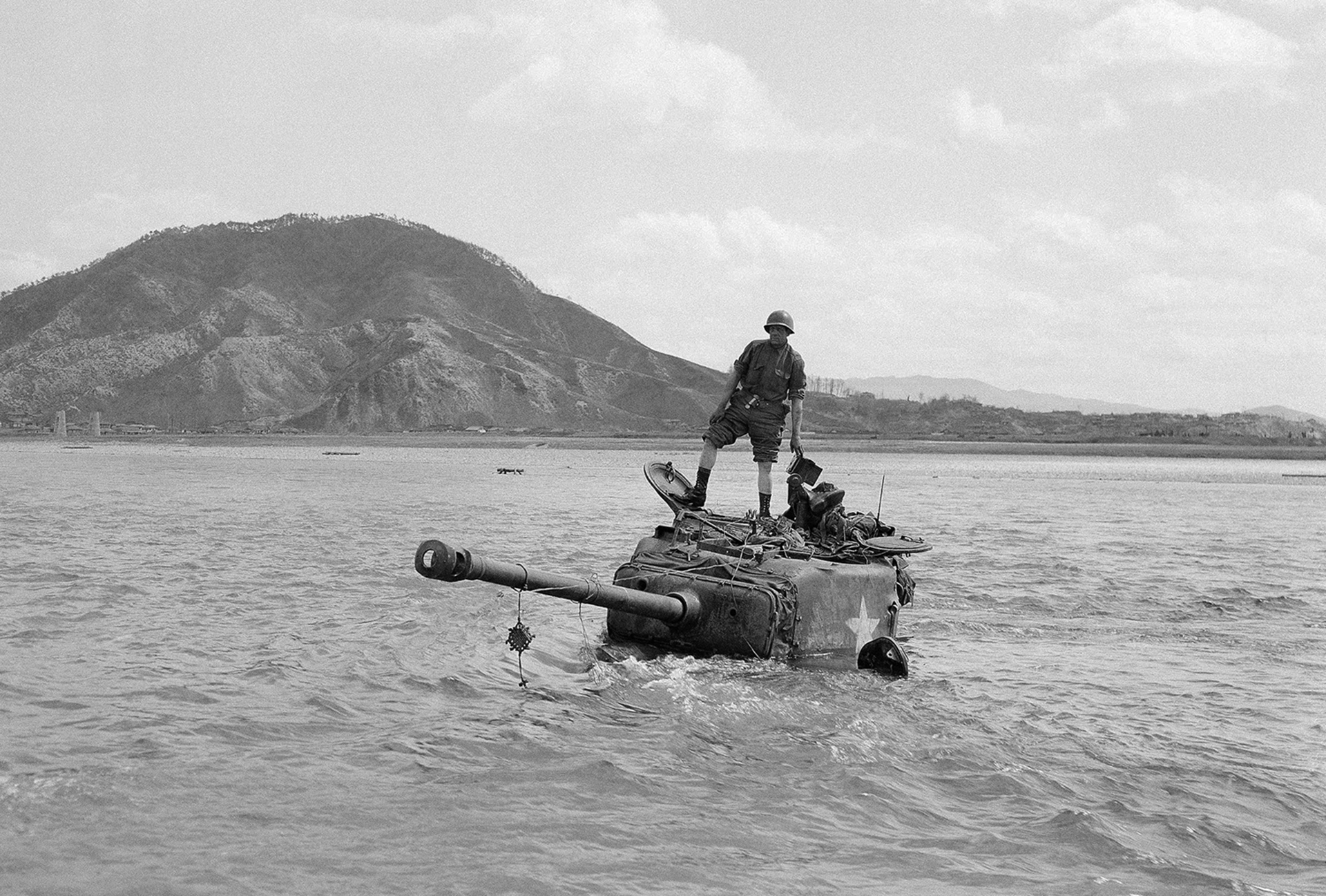 Miembros de la tripulación en la parte superior de su tanque después de quedarse varados durante una inmersión en el río Pukhan. El tanque fue remolcado a un lugar seguro el 7 de abril de 1951 en Corea (AP)