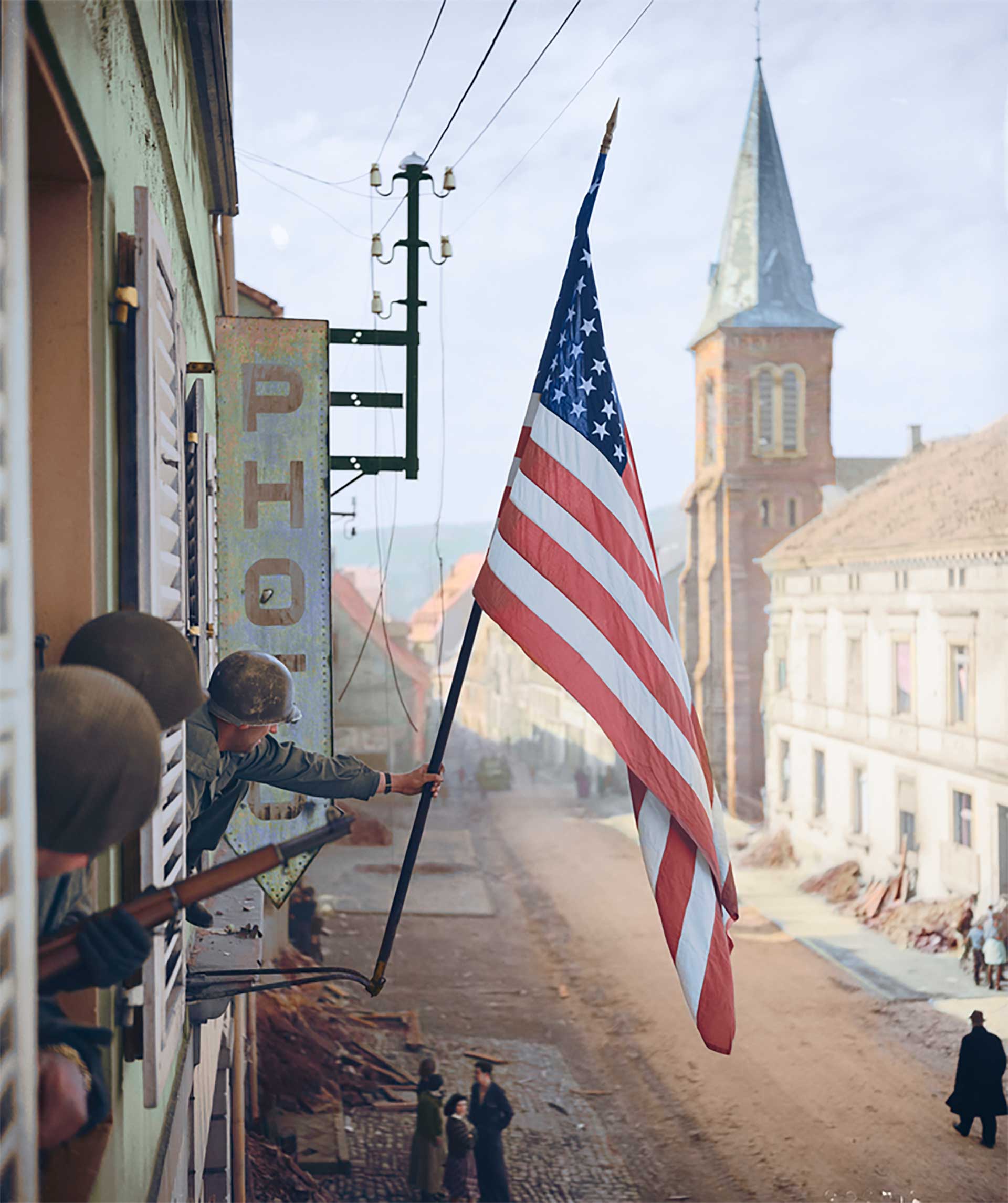El capitán Thomas H. Garrahan, del Regimiento de Infantería 398 iza una bandera de los Estados Unidos en la ciudad francesa de Bitche. La bandera fue confeccionada en secreto por una niña