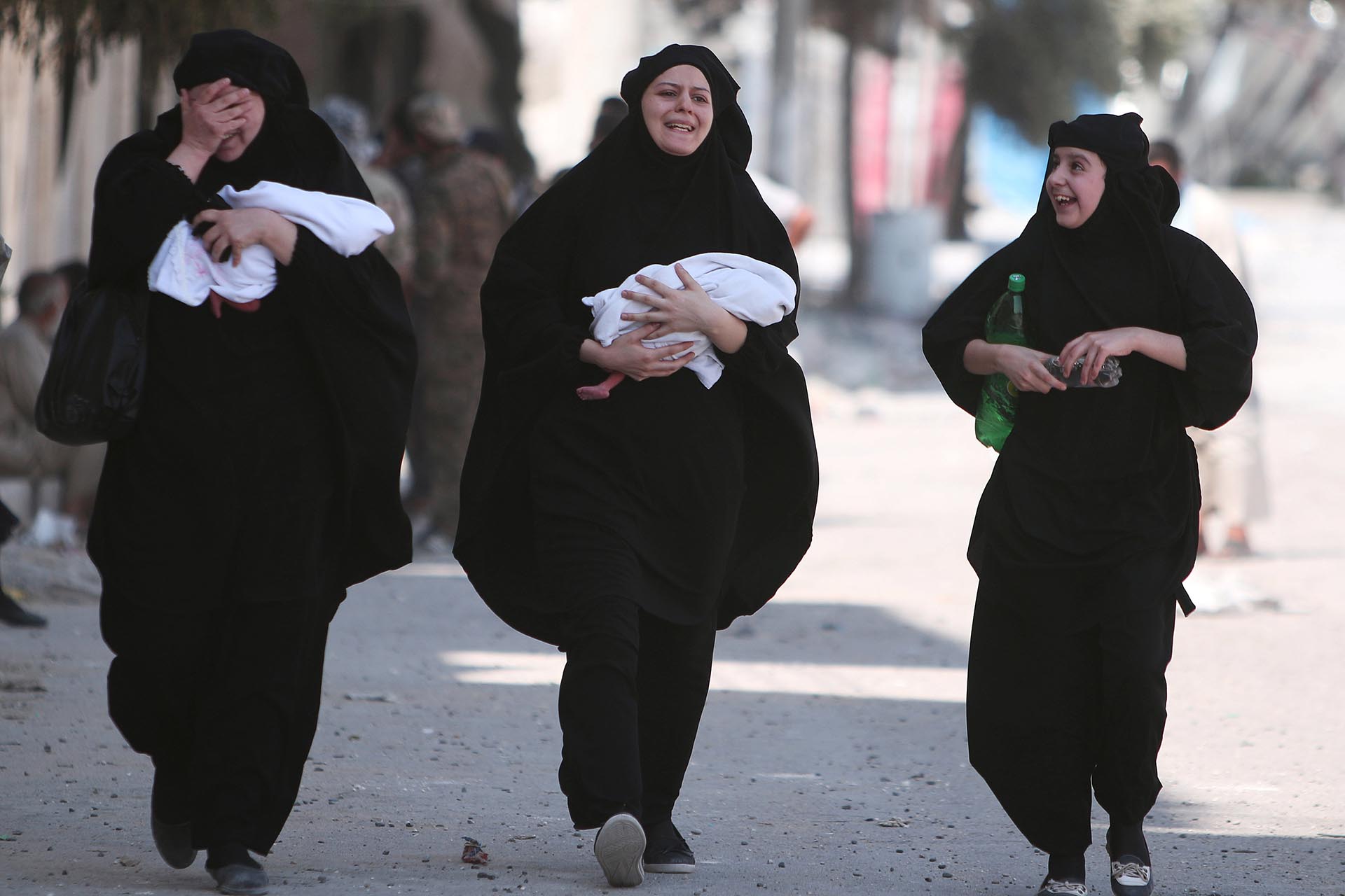 Mujeres lloran de la emoción y llevan a sus bebés recién nacidos en brazos, luego de saber que el Estado Islámico ya no controla su ciudad (Reuters)