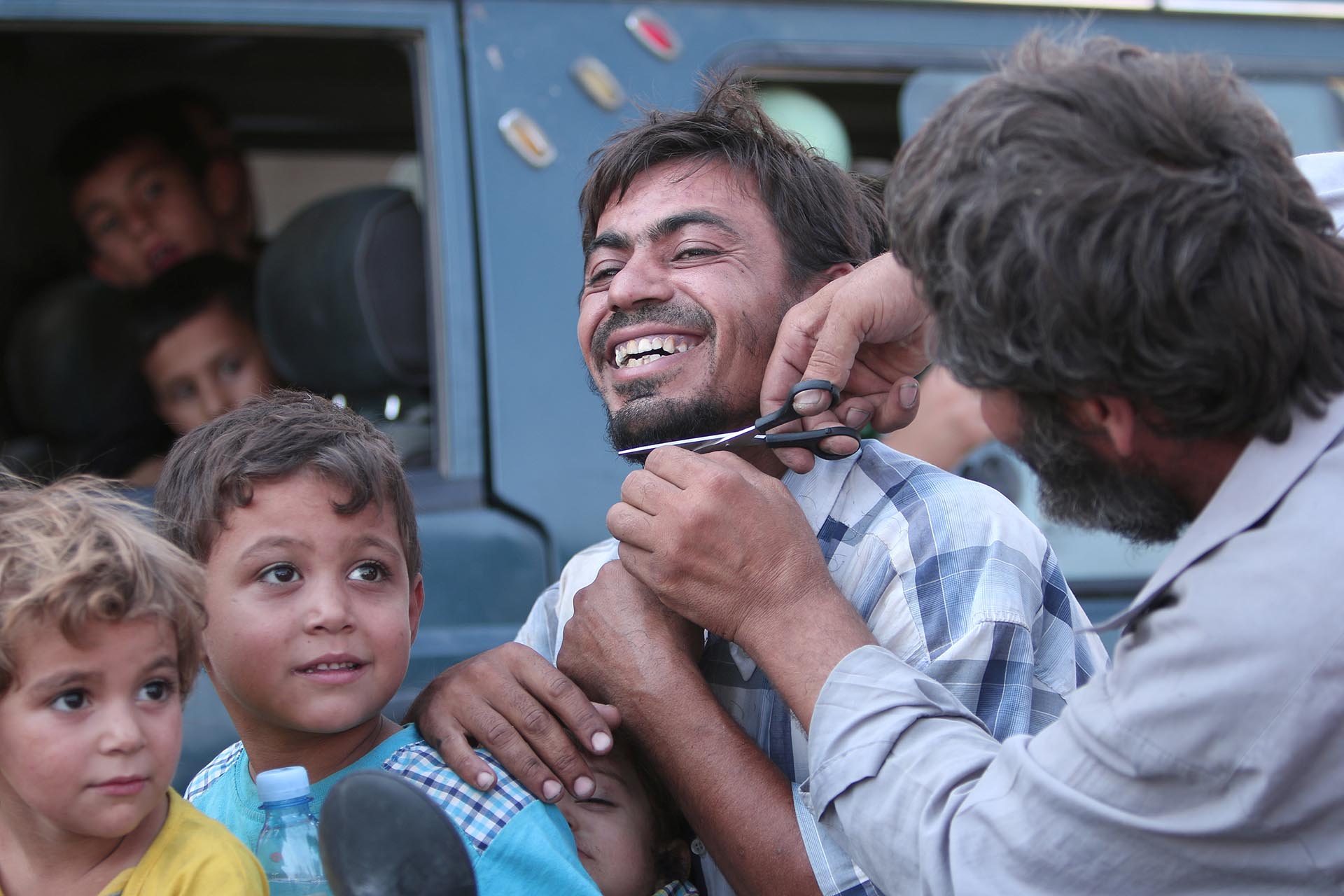 Un hombre corta su barba en público con una sonrisa única. ISIS obligaba a los habitantes de Manbij a usar una barba tupida, como dicta el islam radical (Reuters)