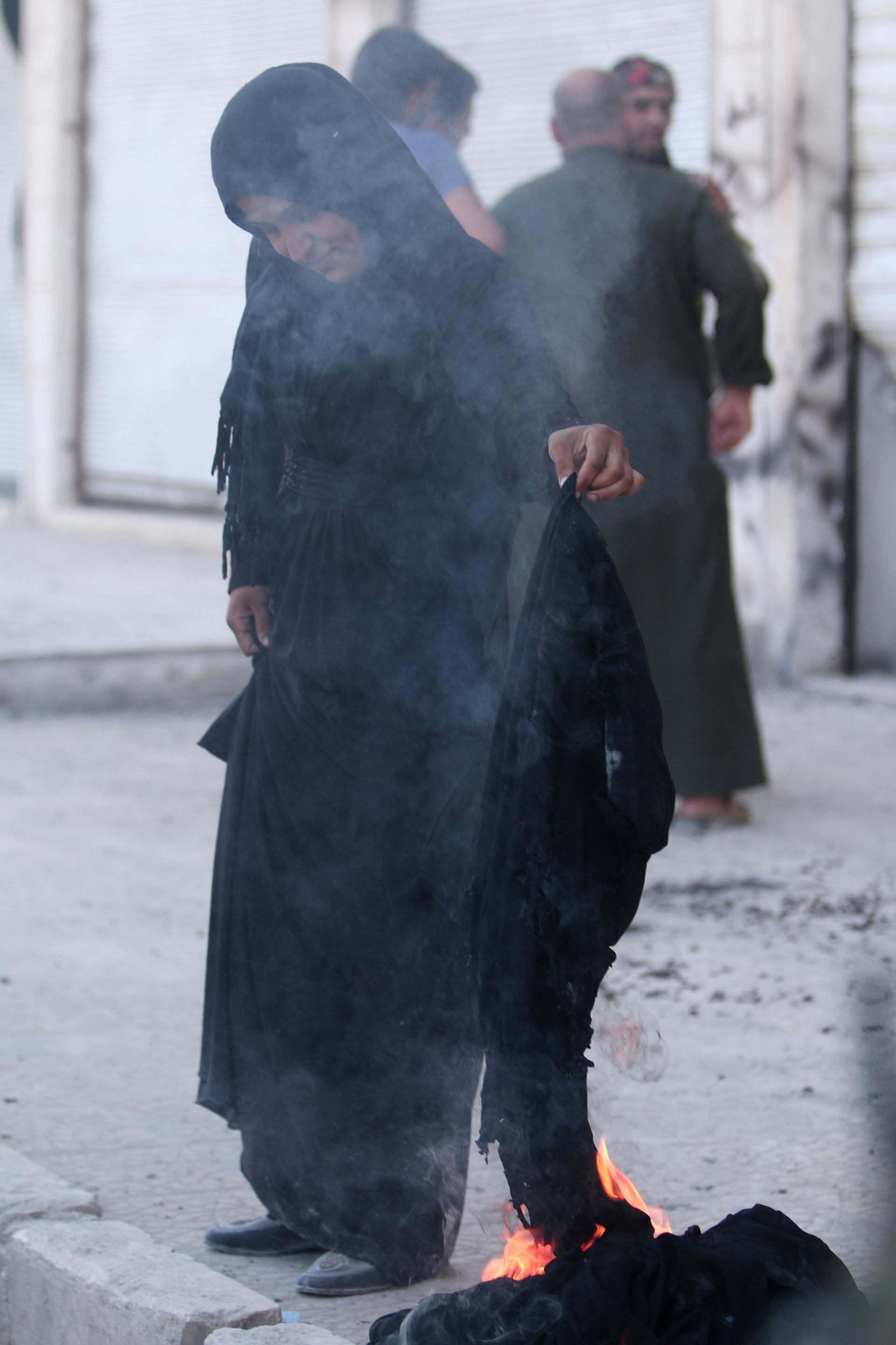 Una mujer quema su niqab luego de saber que el Estado Islámico ya no la obligaría a usarlo. Los terroristas fueron expulsados de la ciudad de Manbij gracias al asedio de una fuerza árabe-kurda con apoyo norteamericano (Reuters)