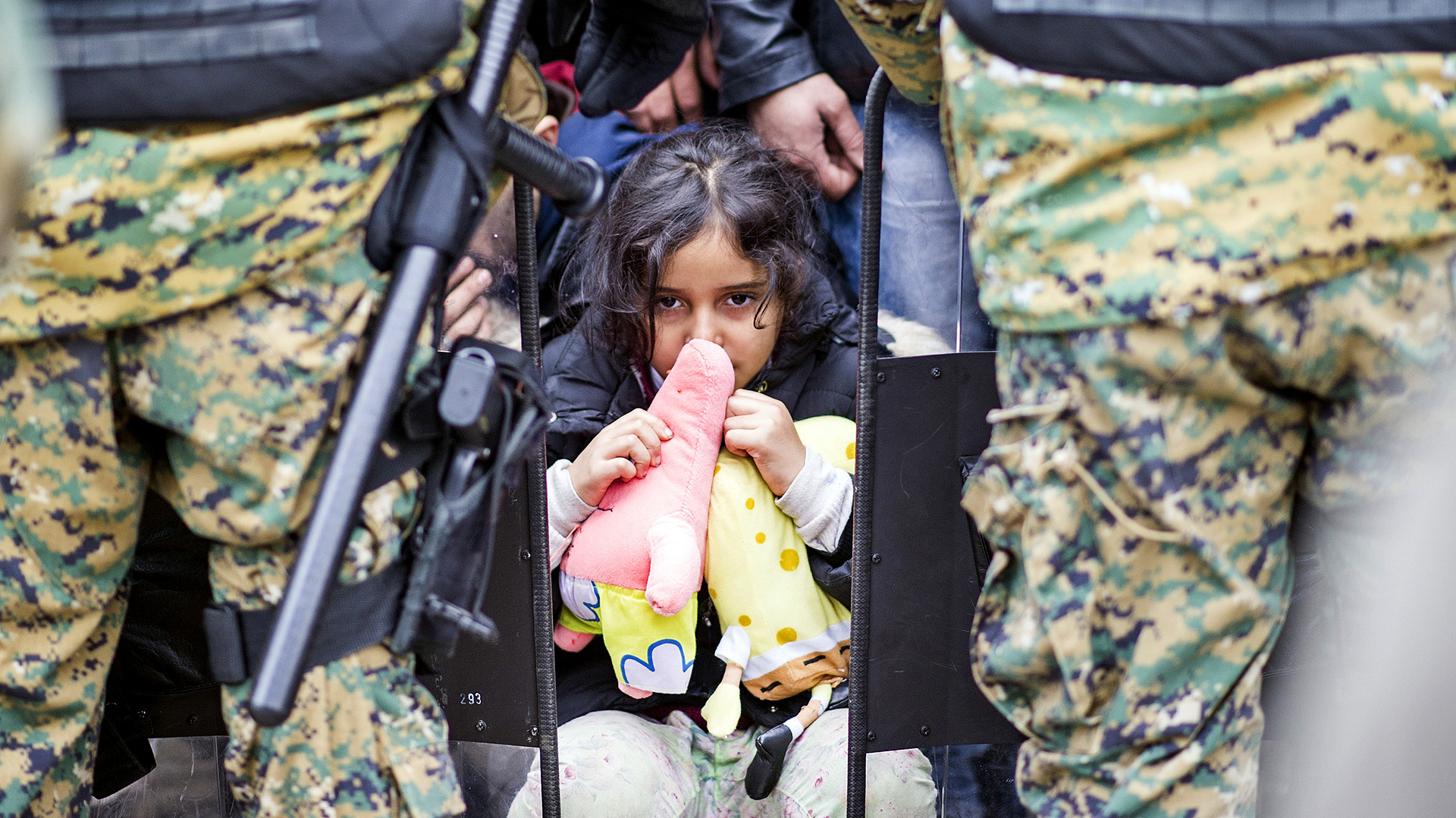 Un niña aguarda entre los oficiales de la policía macedonia para intentar ingresar en Grecia. ROBERT ATANASOVSKI / (AFP)