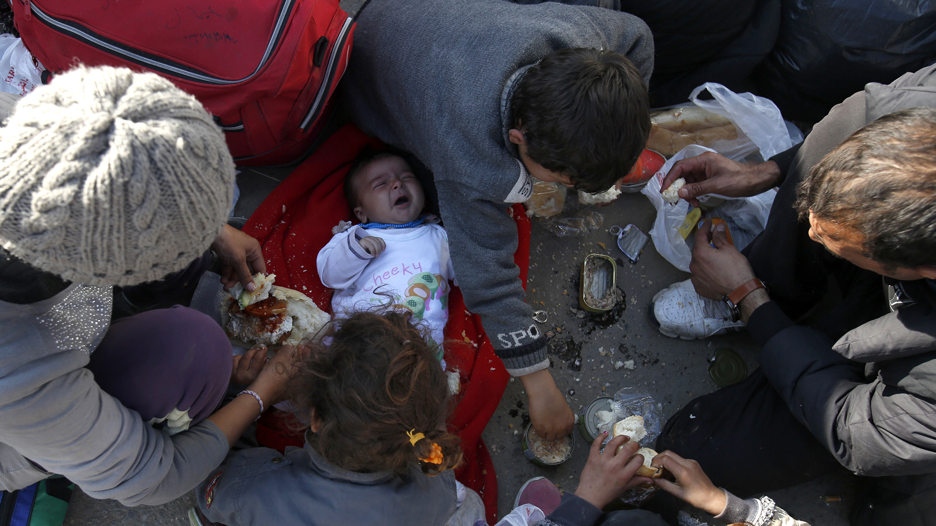 Migrantes comen mientras esperan para registrarse en un centro de refugiados de la ciudad de Presevo, al sur de Serbia. (AP/Darko Vojinovic)