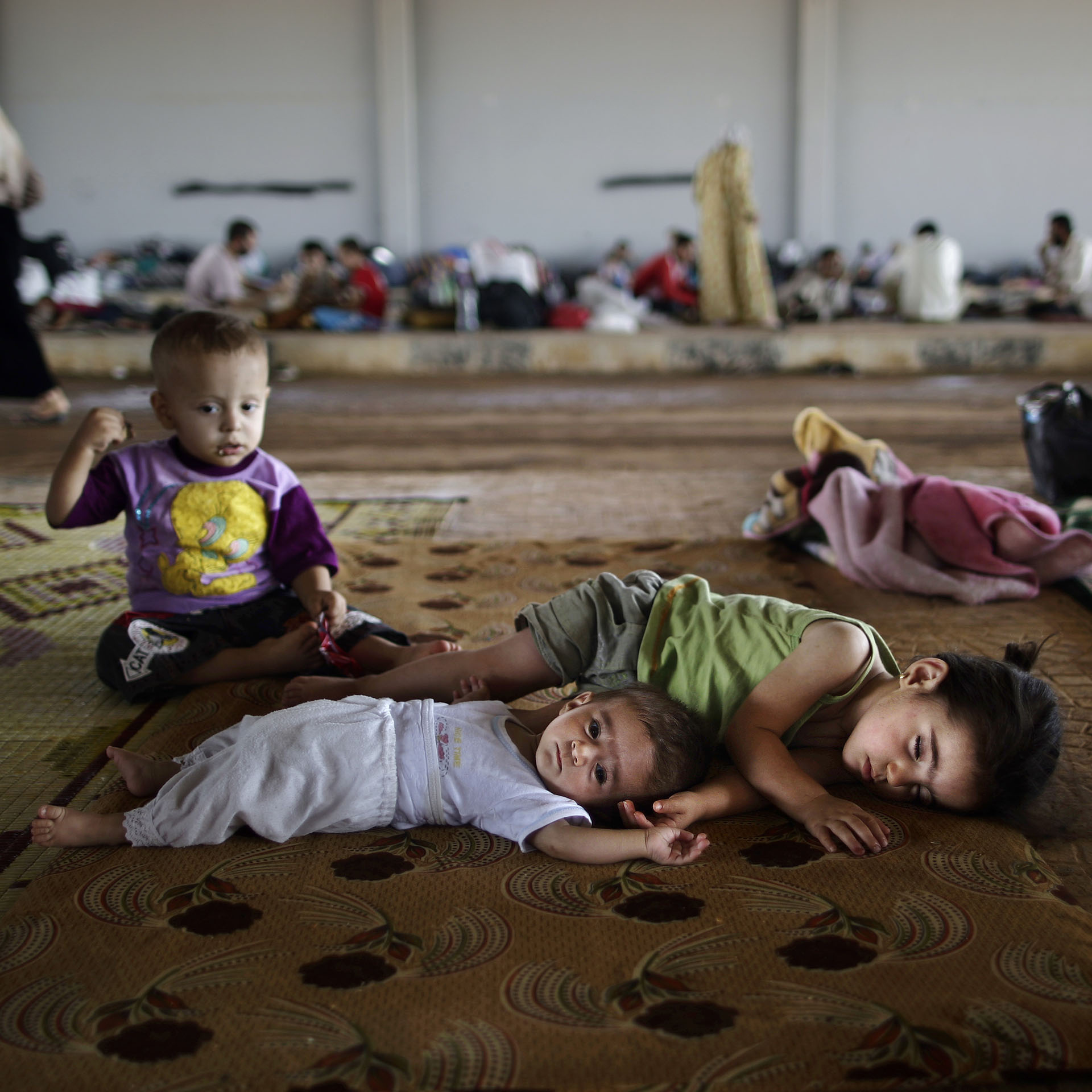 Niños sirios que huyeron de sus ciudades junto a sus familias, aguardan en el puesto aduanero de Bab Al-Salameh para lograr ingresar a un campo de refugiados en Turquía (AFP)