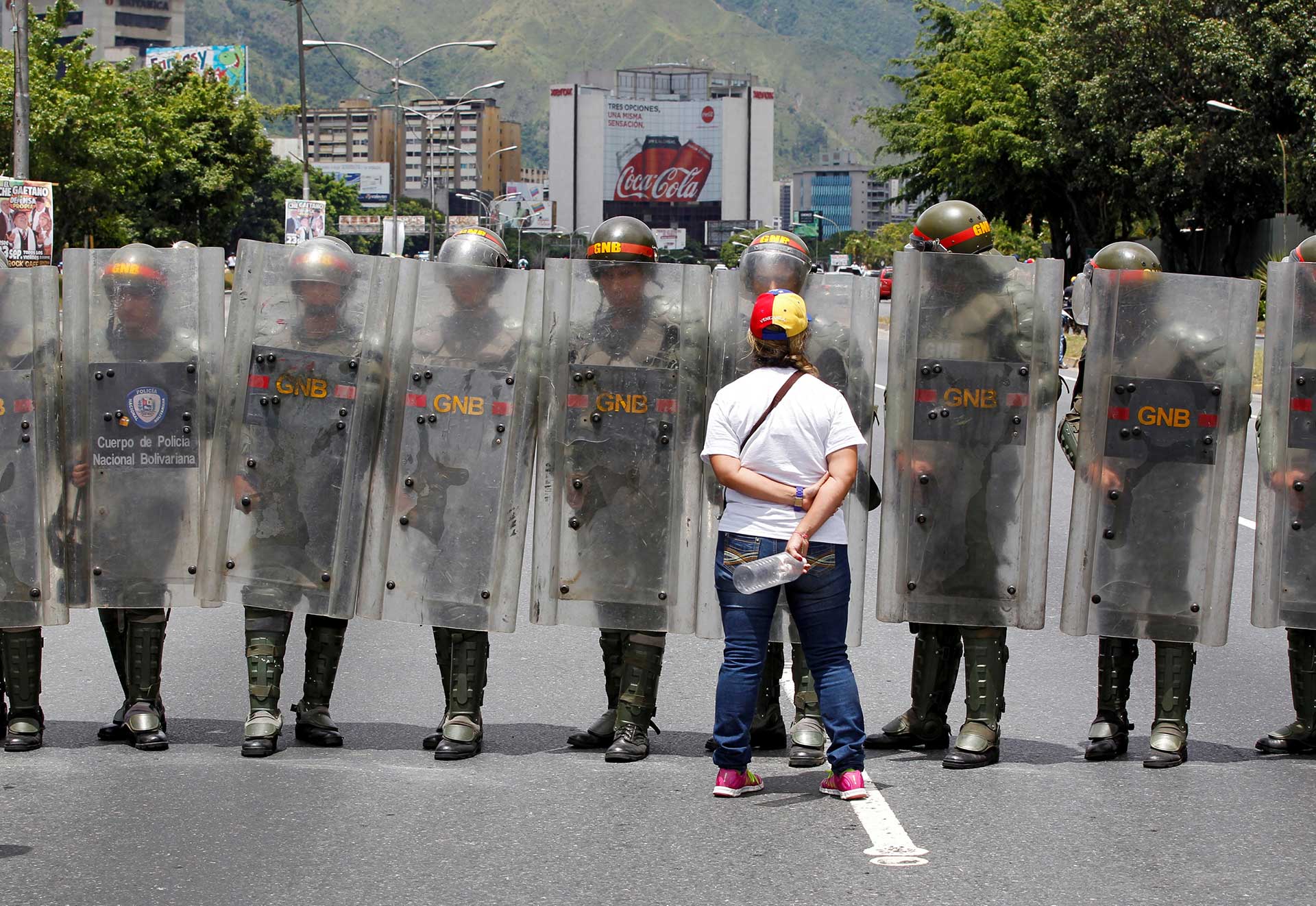 Una mujer se para delante de policías que bloquean la calle (Reuters)