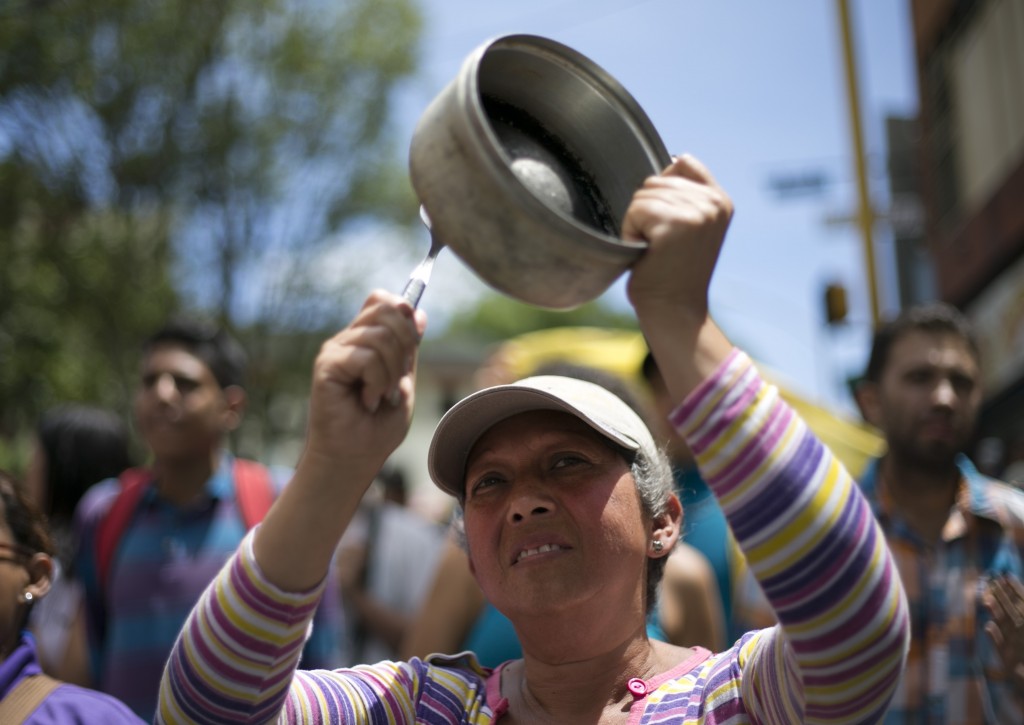 A woman bangs a pot to protest Venezuela's President Nicolas Maduro in Los Teques on the outskirts of Caracas, Venezuela, Wednesday, Sept. 7, 2016. Venezuelans are marching in cities across the country to demand authorities allow a recall referendum against Maduro to go forward this year. (AP Photo/Ariana Cubillos)