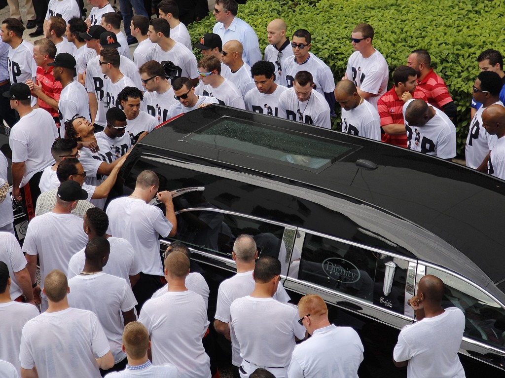 Jugadores de los Miami Marlins caminan al costado del coche fúnebre mientras sale del Estadio (AP)
