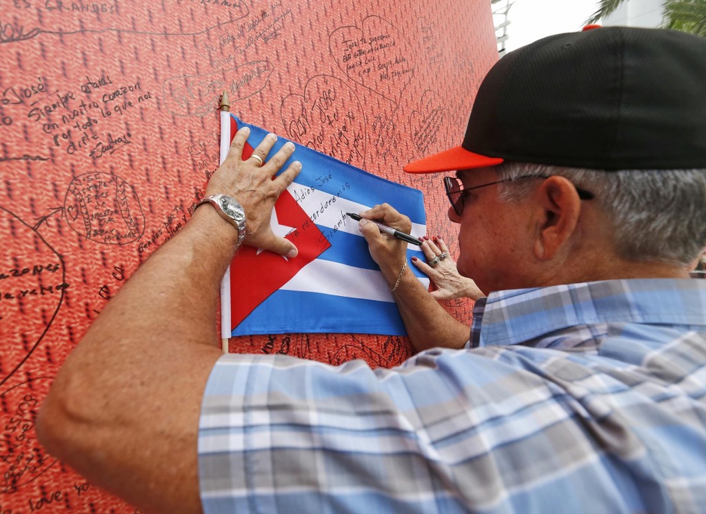 El fanático Juan De Feria escribe un mensaje para Fernández en una bandera cubana (AP)