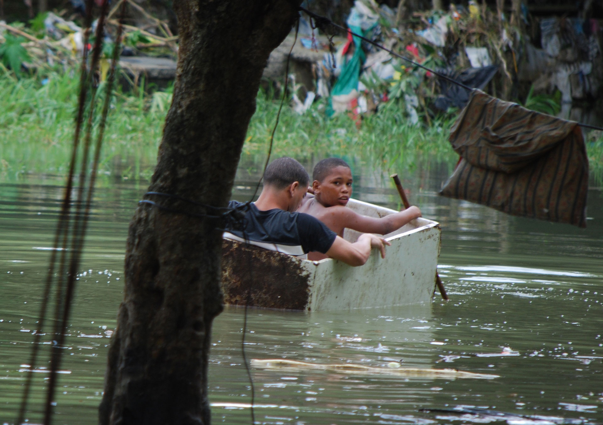 Dos niños flotan en el medio del agua a bordo de un improvisado bote (AP)